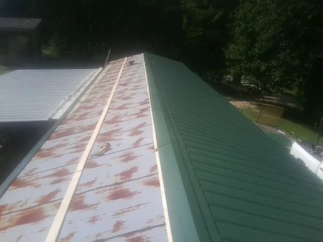 Old rusted panels beside newly installed green metal roofing — Wind Damage Roof Repair by Roofing Brothers in Tonawanda