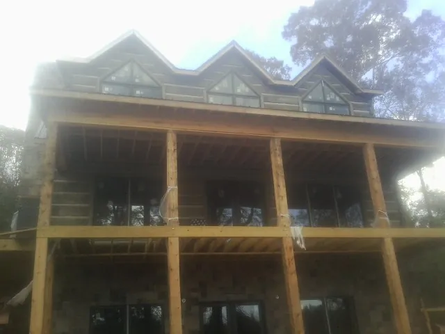 Dormers and porch framing on a large log home under construction — Roof Coating work by our crew in Tonawanda