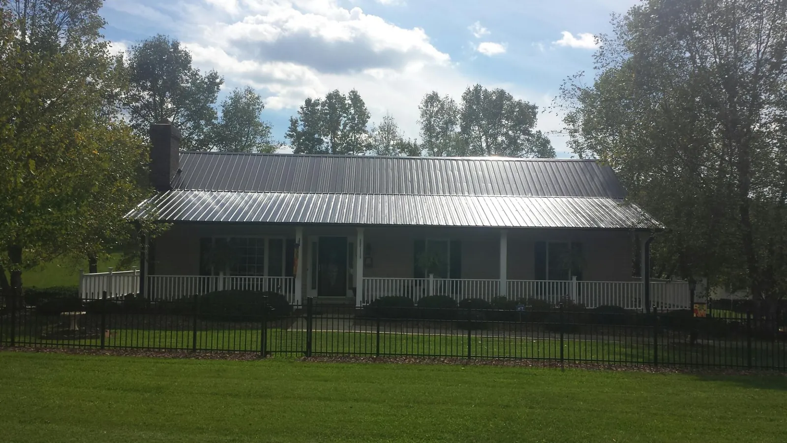 Gray metal roof on a brick ranch with a full width front porch — Gutter Guard Installation work by our crew in Tonawanda
