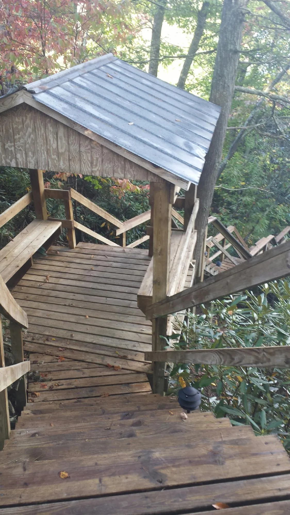 Metal roofed shelter over wooden steps on a wooded walkway — Skylight Repair & Installation work by our crew in Tonawanda