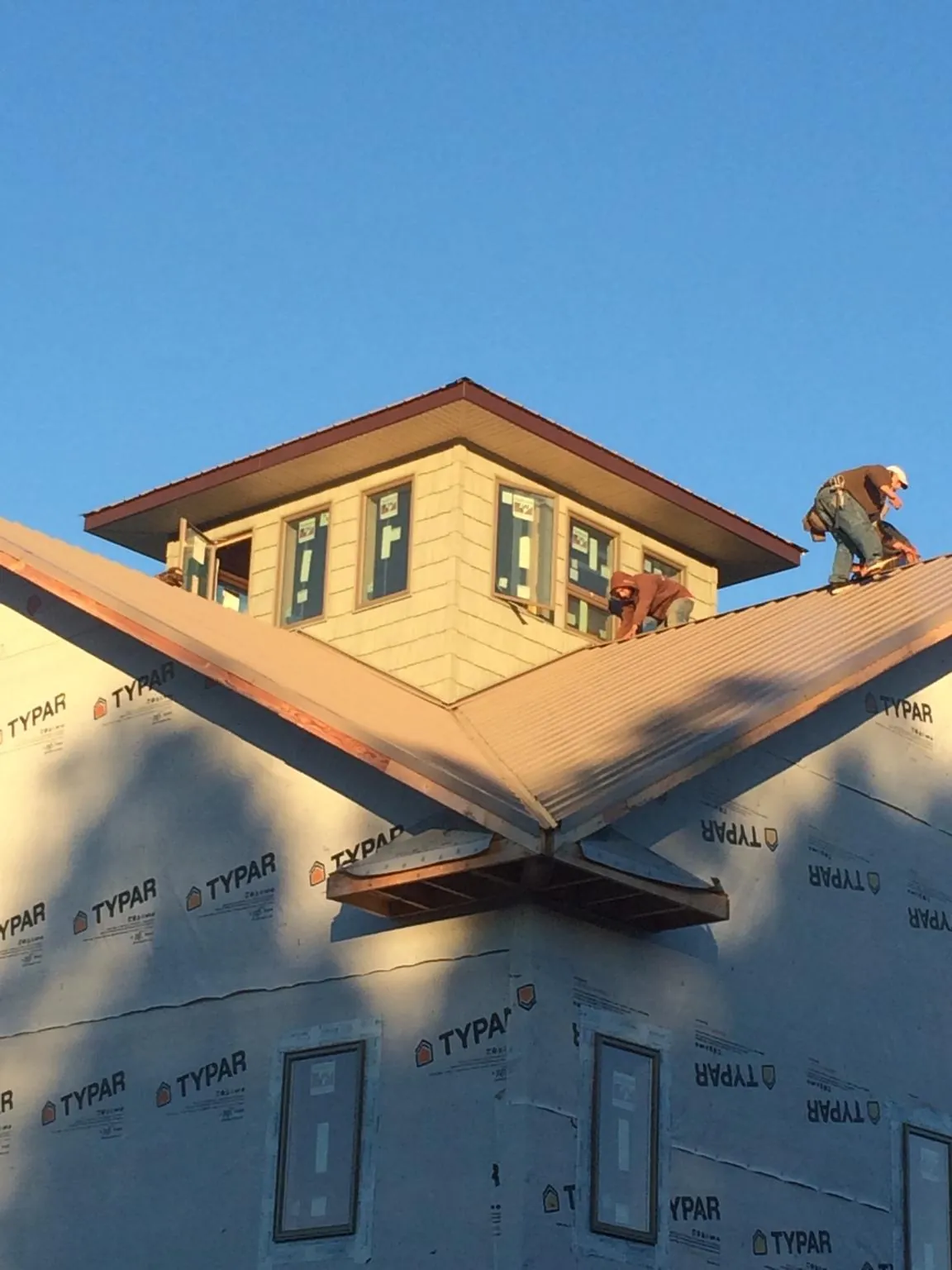 Roofers working around a rooftop cupola on a new metal roof at sunset — Roof Waterproofing in Tonawanda by Roofing Brothers